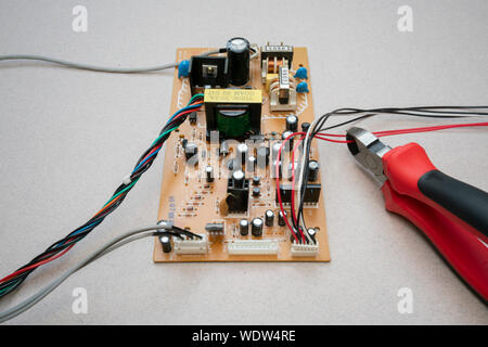 a circuit board with wires and a set of wire cutters cutting a wire Stock Photo