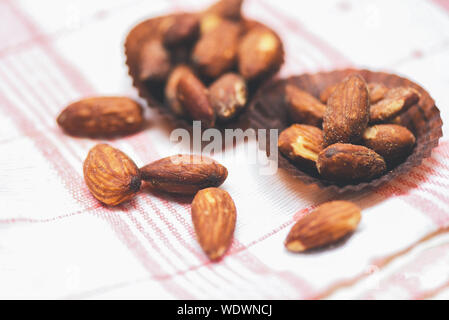 Almonds roasted in a cup on tablecloth , close up almonds nuts baked salt Stock Photo