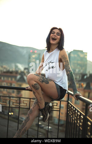 Portrait Of Laughing Young Woman With Tattoos Against Clear Sky