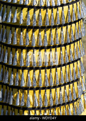 Close up of pow wow jingle dress in gold with black ribbon and silver lids formed into conical bells worn by a Native American woman at a pow wow. Stock Photo