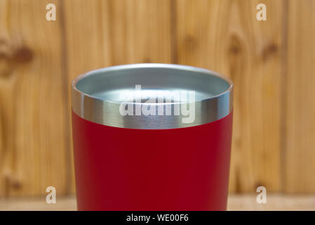 Red colour stainless steel tumbler or cold and hot storage cup on wooden background. Stock Photo