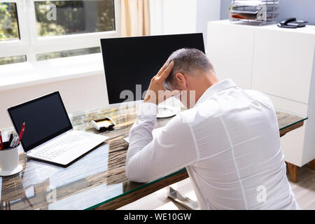 Young Depressed businessman Sitting At Office Desk Stock Photo