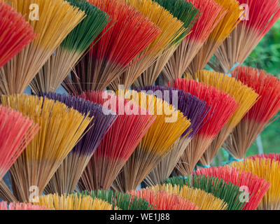 Close up of bundles of incence sticks in pink, yellow, purple and green for sale at a roadside shop in Vietnam. Stock Photo