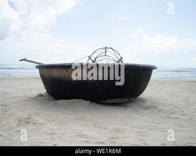 Iconic Vietnamese basket boat for fishing on a sandy beach in Danang with the sea in the background. Photographed at eye level. Stock Photo