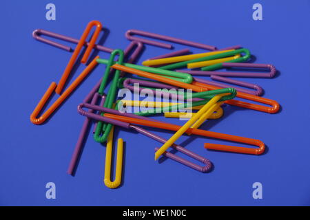A lot of plastic tubules for drinks. Blue background. Close-up of straw tubes. Colorful trendy drinking straws, colored tubes for a party on a blue ba Stock Photo