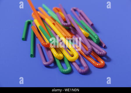 A lot of plastic tubules for drinks. Blue background. Close-up of straw tubes. Colorful trendy drinking straws, colored tubes for a party on a blue ba Stock Photo