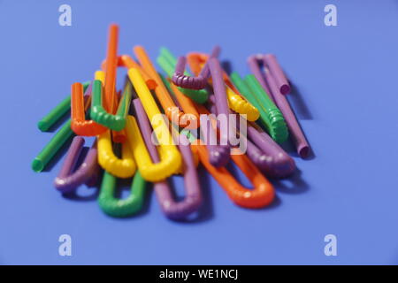 A lot of plastic tubules for drinks. Blue background. Close-up of straw tubes. Colorful trendy drinking straws, colored tubes for a party on a blue ba Stock Photo