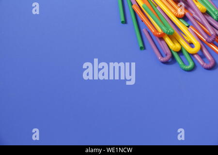 A lot of plastic tubules for drinks. Blue background. Close-up of straw tubes. Colorful trendy drinking straws, colored tubes for a party on a blue ba Stock Photo