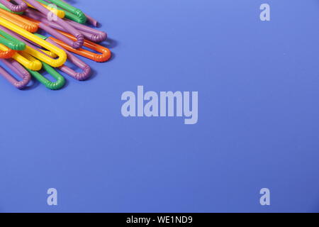 A lot of plastic tubules for drinks. Blue background. Close-up of straw tubes. Colorful trendy drinking straws, colored tubes for a party on a blue ba Stock Photo