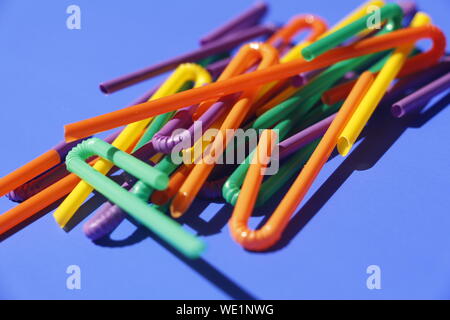 A lot of plastic tubules for drinks. Blue background. Close-up of straw tubes. Colorful trendy drinking straws, colored tubes for a party on a blue ba Stock Photo