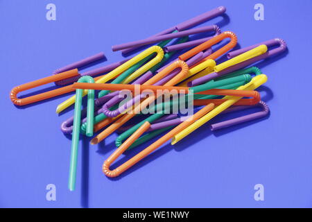 A lot of plastic tubules for drinks. Blue background. Close-up of straw tubes. Colorful trendy drinking straws, colored tubes for a party on a blue ba Stock Photo