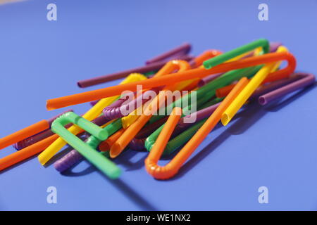 A lot of plastic tubules for drinks. Blue background. Close-up of straw tubes. Colorful trendy drinking straws, colored tubes for a party on a blue ba Stock Photo