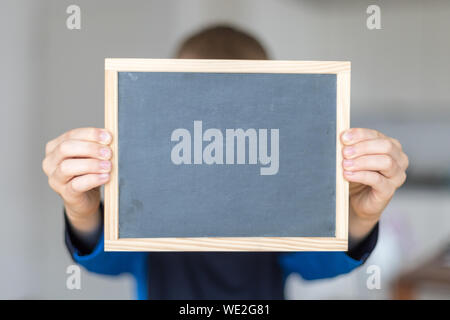 a boy holding an empty white board in a classroom Stock Photo - Alamy