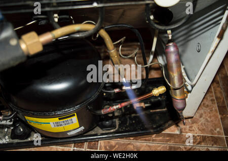 Refrigerator repair - a tool to repair a refrigerator and the repair process itself, a view of a refrigerator unit Stock Photo