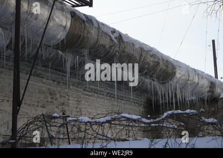 Industrial thick pipe in a company with large icicles in winter in frost Stock Photo