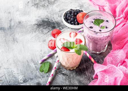 Fruit smoothies with black currant, strawberry, banana and peach and pieses fruits on gray concrete background, copy space,  Concept  healthy lifestyl Stock Photo