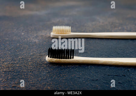 two wooden eco brushes with natural bristles on dark concrete background. Plastic free set. Zero waste, eco friendly concept. Stock Photo