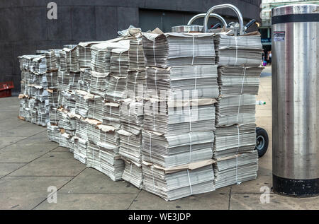 Rows of newspaper stacks lined up on a pavement, London, England, UK. Stock Photo