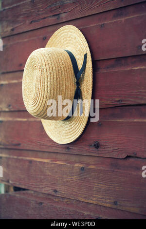 Straw hat hanging on wooden hanger 