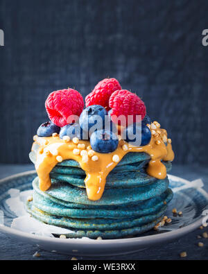 Blue spirulina pancakes topped with peanut butter and berries Stock Photo