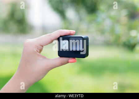 Making a selfie with action camera concept. Camera in woman hand. Close-up. Stock Photo