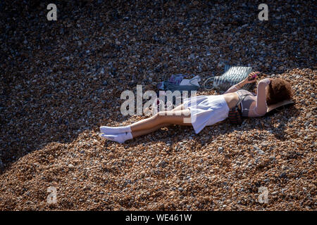 young woman lying on brighton beach texting Stock Photo