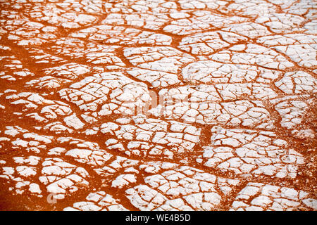 Cracked white dry clay and orande sand texture surface close up top view in Namib Desert, Southern Africa Stock Photo