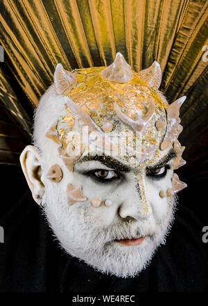 Head with thorns or warts, face covered with glitters, close up. Fantasy concept. Alien, demon, sorcerer makeup. Senior man with beard, with monster Stock Photo