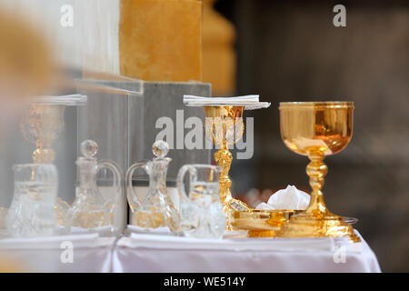 Golden chalice on the altar and ampoules with wine and water before the mass Stock Photo