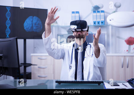 Smart doctor wearing virtual reality goggles in modern clinic office. Doctor with stethoscope. Stock Photo