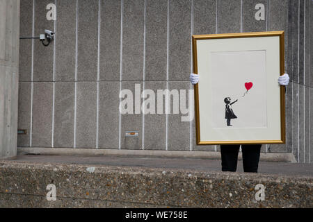 London, UK. 30th Aug, 2019. A Christie's employee poses with artworks 'Girl with balloon' by anonymous street artist Banksy at the Southbank Centre in London Friday, August 30, 2019. The Southbank Centre was near one of the original locations the artwork appeared in London. The screen prints will be on sale during an online only auction titled 'Banksy : I can't believe you morons buy this sh*t' presented by Christie's auction house between 11-24 September 2019. Photograph Credit: Luke MacGregor/Alamy Live News Stock Photo