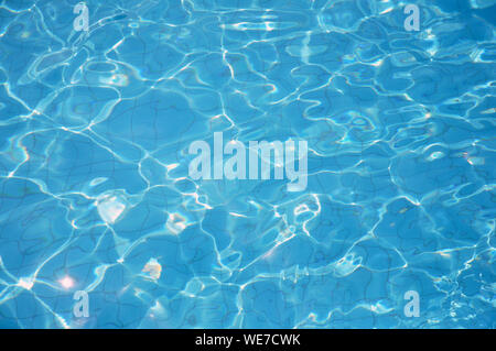 Swimming pool bottom caustics ripple and flow with waves background. Summer background. Texture of water surface. Overhead view. Stock Photo