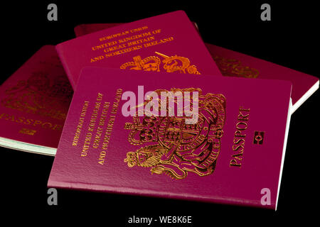 A stack of old and new UK passports isolated on a black background Stock Photo