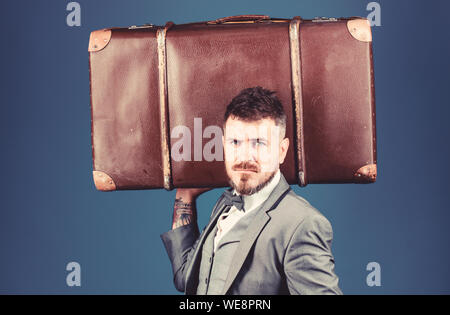 heavy bag. mature traveller. bearded man in formal suit. stylish esthete with vintage bag. businessman in bow tie. business trip with retro suitcase. Elegance and style. Trendy and handsome. Stock Photo