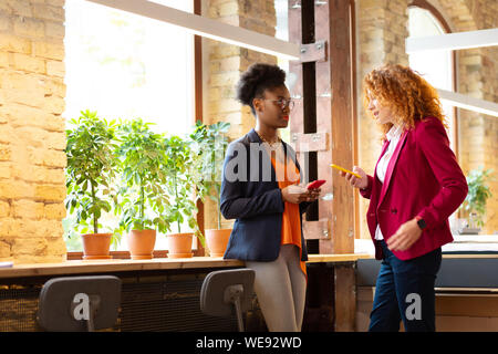 Two office workers using smartphones while having break Stock Photo