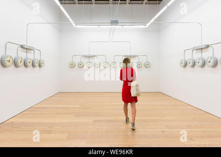 Art gallery woman time, view of a woman in a red dress looking at National Times by Agustina Woodgate in the Whitney Museum Of American Art, NYC, USA Stock Photo