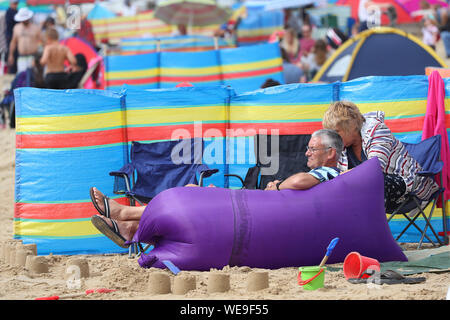 Bournemouth Dorset 30th August 2019. UK weather: Beachgoers on Bournemouth Beach brave a windy start to the day. Credit Stuart Martin/ Alamy Live News Stock Photo