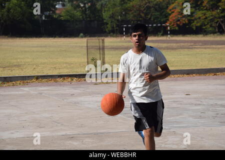 Young Man Playing Basketball On Court
