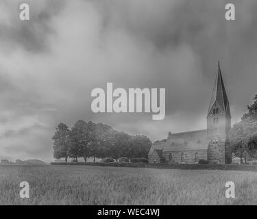 The early morning fog starts to clear at Sonnarslov church in the Skane region of Sweden. Stock Photo