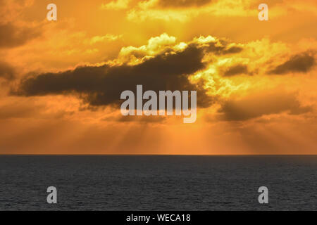 Dramatic sunset with clouds and orange sky over Caribbean sea - colorful sunset light rays - clouds and sun rays | sunrays - Caribbean Sunset Stock Photo