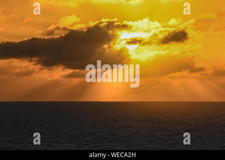 Dramatic sunset with clouds and orange sky over Caribbean sea - colorful sunset light rays - clouds and sun rays | sunrays - Caribbean Sunset Stock Photo