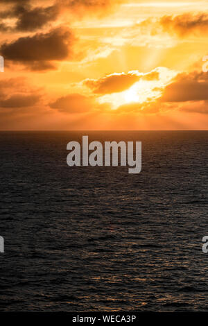 Dramatic sunset with clouds and orange sky over Caribbean sea - colorful sunset light rays - clouds and sun rays | sunrays - Caribbean Sunset Stock Photo