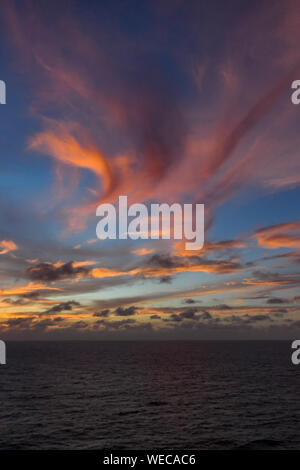 Dramatic sunset with clouds and calm sea - Caribbean sea - colorful sunset and calm ocean - pink clouds and orange clouds in Caribbean Sunset Stock Photo