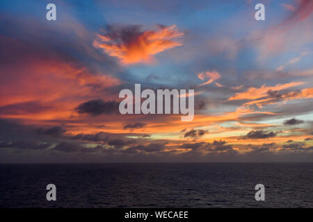 Dramatic sunset with clouds and calm sea - Caribbean sea - colorful sunset and calm ocean - pink clouds and orange clouds in Caribbean Sunset Stock Photo