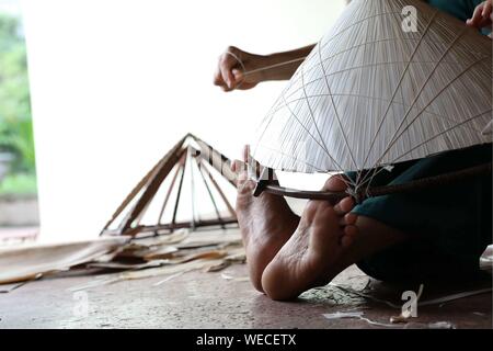 (190830) -- HANOI, Aug. 30, 2019 (Xinhua) -- A local villager makes a traditional conical hat in the Chuong village on the outskirts of Hanoi, capital of Vietnam on Aug. 29, 2019. Vietnam's traditional conical hats are mostly made from bamboo and palm leaves, and they are among the country's most impressive traditional costumes. People in the Chuong village have been making conical hats for about 400 years. The locals buy green palm leaves from other provinces, dry them in the sun and iron and bleach the leaves into flat slices. They then use thin strings to fix layers of leaves on a cone made Stock Photo