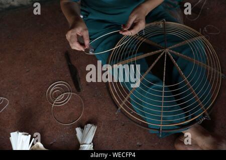 (190830) -- HANOI, Aug. 30, 2019 (Xinhua) -- A local villager prepares a bamboo cone to make a traditional conical hat in the Chuong village on the outskirts of Hanoi, capital of Vietnam on Aug. 29, 2019. Vietnam's traditional conical hats are mostly made from bamboo and palm leaves, and they are among the country's most impressive traditional costumes. People in the Chuong village have been making conical hats for about 400 years. The locals buy green palm leaves from other provinces, dry them in the sun and iron and bleach the leaves into flat slices. They then use thin strings to fix layers Stock Photo