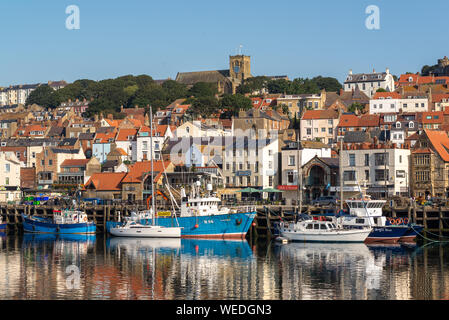 Fishing boats moored in the harbour below the church on the hill, South Bay, Scarborough, North Yorkshire, UK Stock Photo
