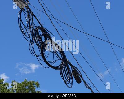 Close upward shot of tangled wires hanging from a power line Stock Photo