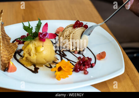 A man eats coal and chicory ice cream, decorated with waffles and fresh berries. Stock Photo