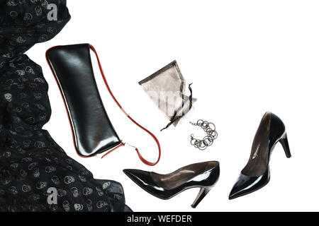 Halloween party female outfit layout of accessories black on white background: shoes, cloth with skulls, jewelry. Stock Photo